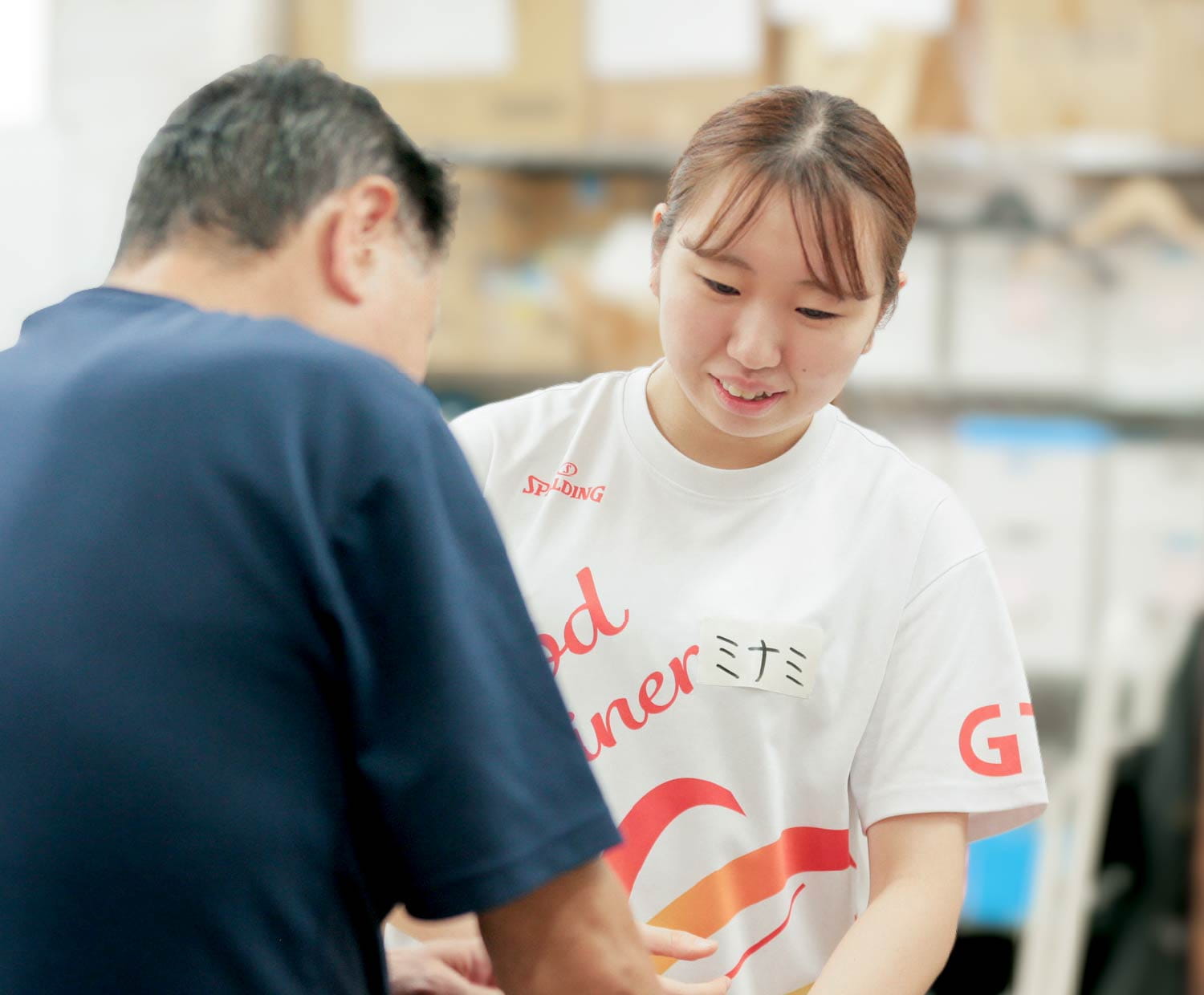 女性トレーナーが男性の腕を手で支え、ストレッチの姿勢を丁寧に誘導している様子