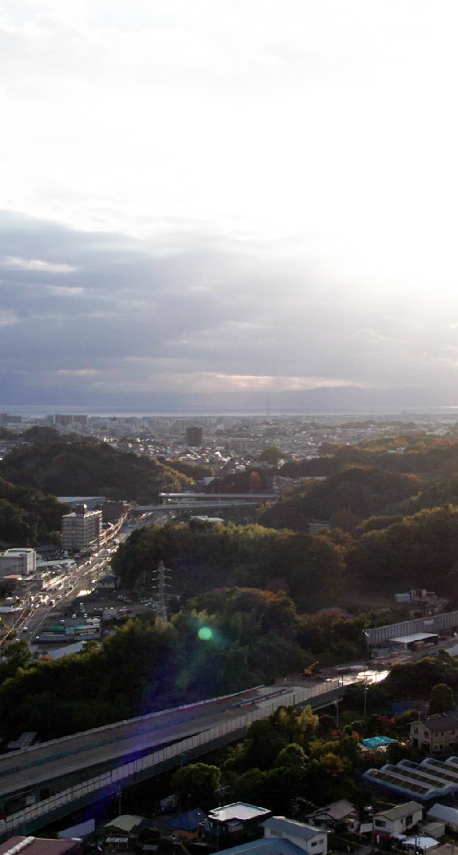 朝日か夕日の光に包まれた、住宅街と道路が広がる高所からの眺め