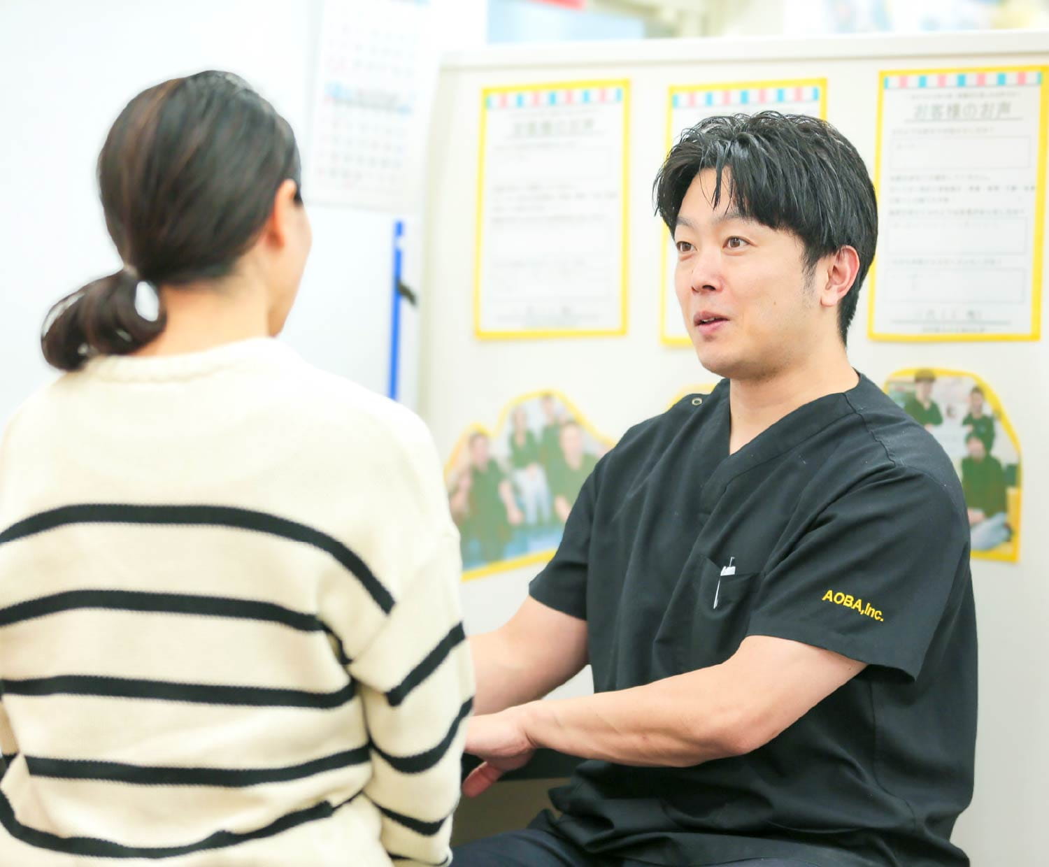イスに座る男性施術者が、施術着の患者と向き合って話をしている様子